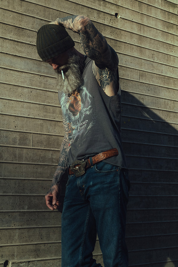 Retrato dirigido en exterior, hombre con gorro y barba junto a un muro de concreto