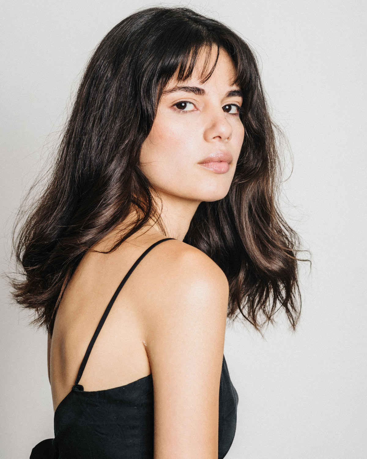 Pola de casting en estudio: modelo de perfil con top negro y fondo blanco.